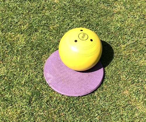 A small, round, purple plastic mat with a   yellow jack sitting on it